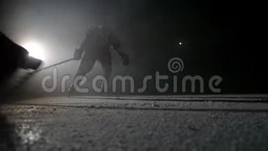 两名曲棍球运动员在竞技场的黑暗中高速刹车时使冰闪闪